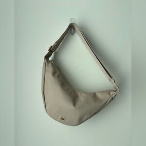 Minimalist July travel sling bag in a neutral light taupe